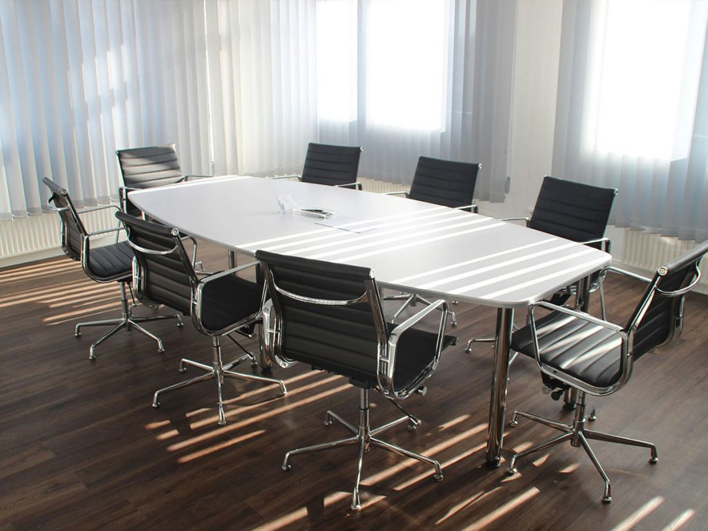 Sauberer Konferenzraum in Nürnberg mit weißem Tisch und schwarzen Lederstühlen nach der Unterhaltsreinigung